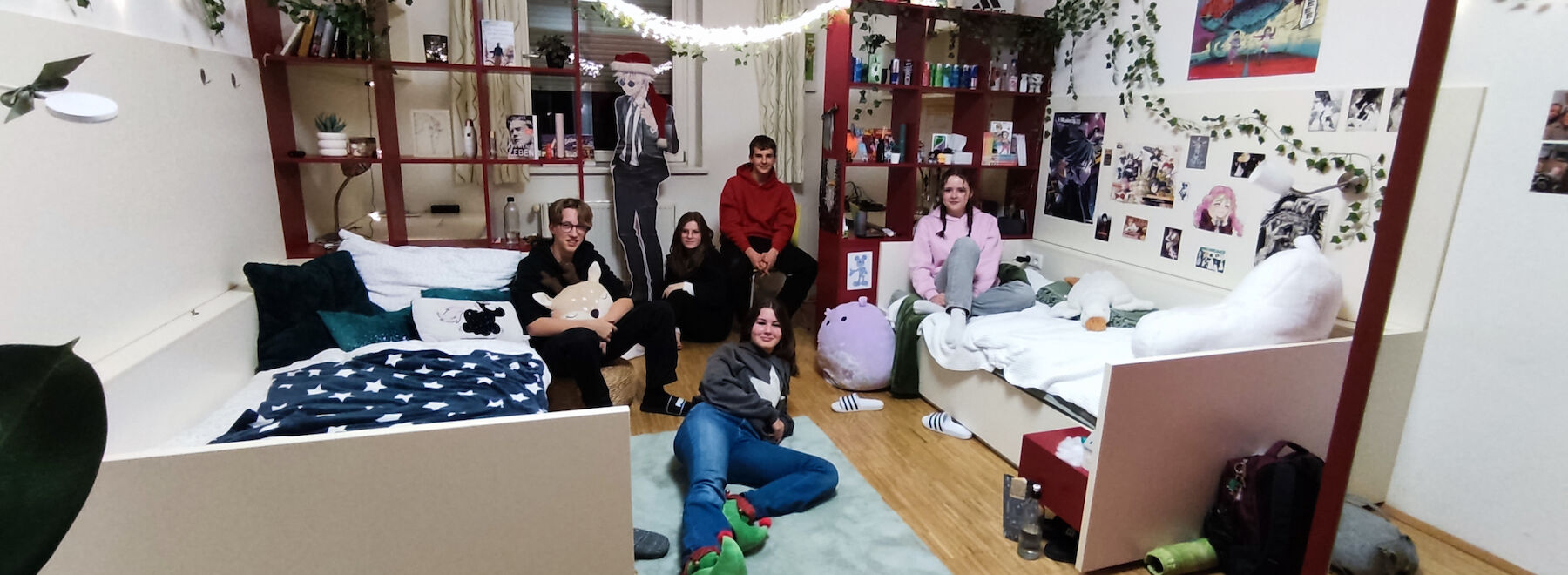 Zwei Menschen lächeln und unterhalten sich in einem dekorierten Raum mit Fotos und Regalen.